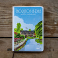 Notebook with a scenic illustration of Thorington-le-Dale, North Yorkshire, on a wooden surface.